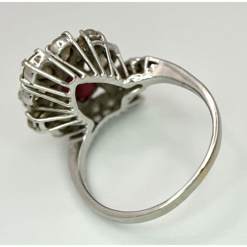 59 - A Vintage 18K White Gold, Ruby and Diamond Ring. An oval ruby with an abstract diamond surround of p... 