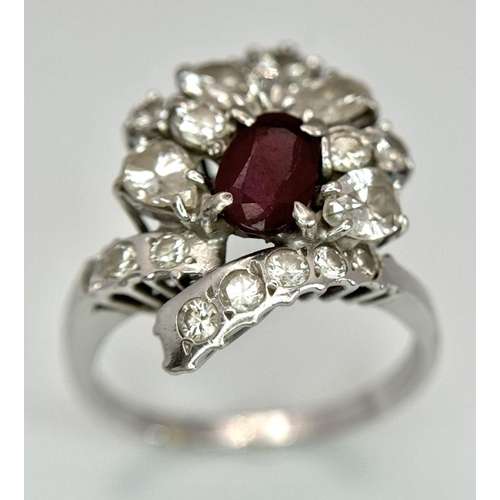 59 - A Vintage 18K White Gold, Ruby and Diamond Ring. An oval ruby with an abstract diamond surround of p... 