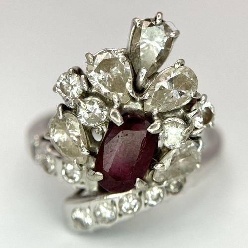 59 - A Vintage 18K White Gold, Ruby and Diamond Ring. An oval ruby with an abstract diamond surround of p... 