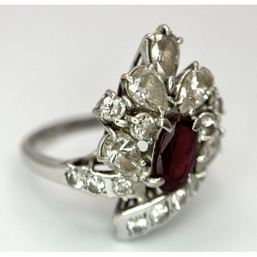 59 - A Vintage 18K White Gold, Ruby and Diamond Ring. An oval ruby with an abstract diamond surround of p... 