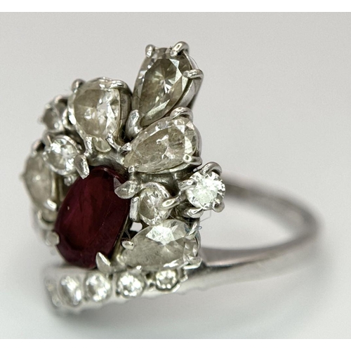 59 - A Vintage 18K White Gold, Ruby and Diamond Ring. An oval ruby with an abstract diamond surround of p... 