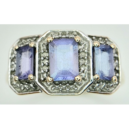 574 - An impressive 9 CARAT GOLD RING having 3 Emerald Cut TANZANITE coloured Gemstones with DIAMOND SURRO... 