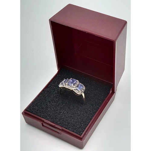 574 - An impressive 9 CARAT GOLD RING having 3 Emerald Cut TANZANITE coloured Gemstones with DIAMOND SURRO... 