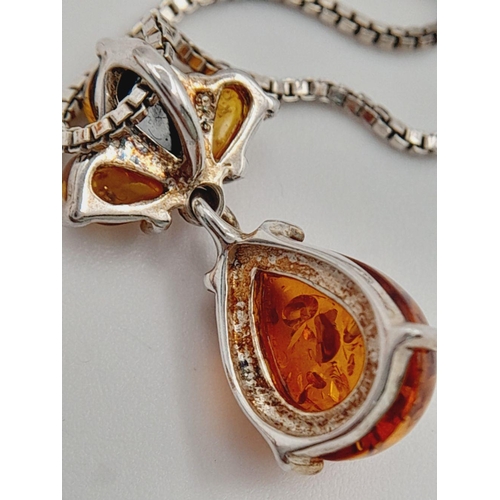 700 - A ‘HOBBS’  AMBER and SILVER PENDANT. Having different shades of Amber set in SILVER and mounted on a... 