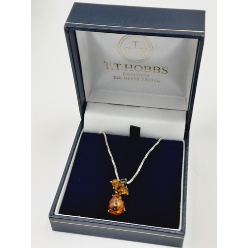 700 - A ‘HOBBS’  AMBER and SILVER PENDANT. Having different shades of Amber set in SILVER and mounted on a... 