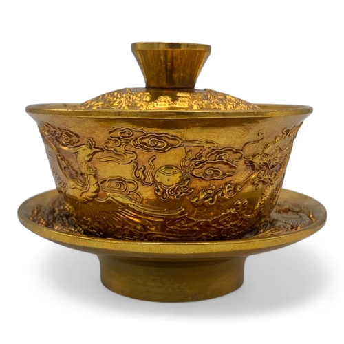 1376 - A Chinese Gold-Toned Dragon and Phoenix Tea Bowl with Saucer.  
Gold-toned bronze exterior with intr... 