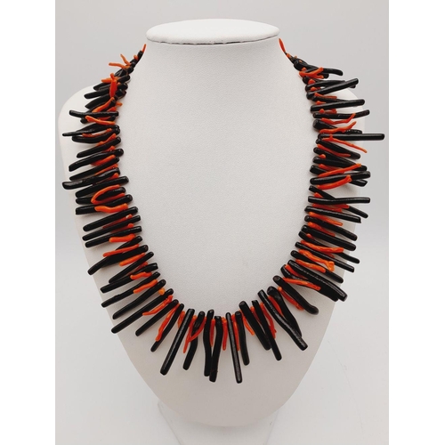 157 - A fascinating necklace and earrings set with a rare combination of black and red corals. In a presen... 