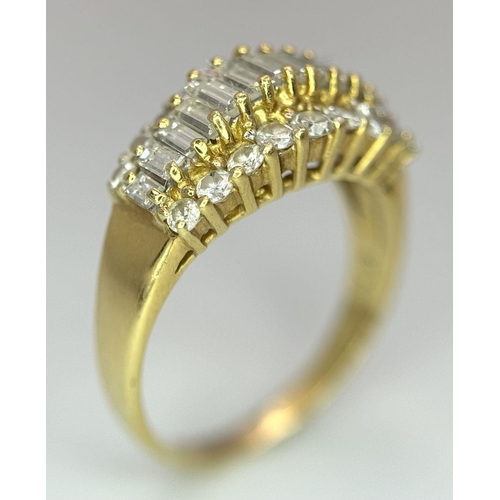 16 - An 18K Yellow Gold Three Row Diamond Ring. An extravagant central row of baguette cut diamonds with ... 