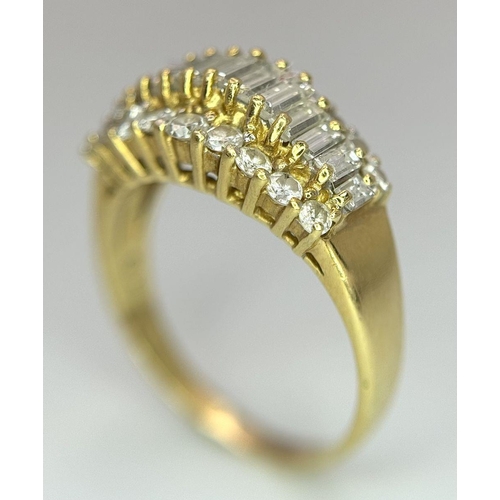 16 - An 18K Yellow Gold Three Row Diamond Ring. An extravagant central row of baguette cut diamonds with ... 