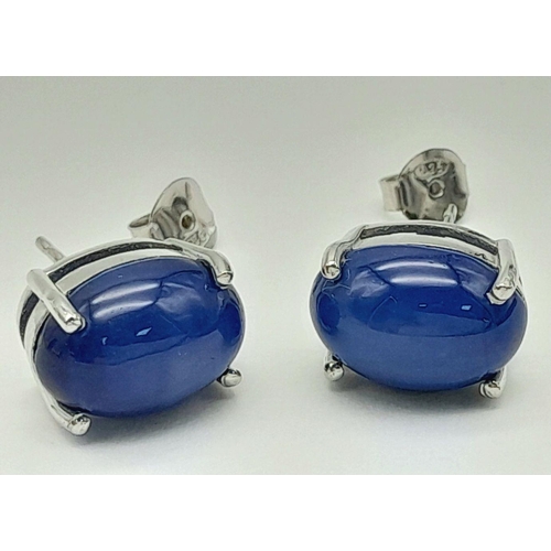 58 - A mesmerising, sterling silver, pair of earrings with a large blue, six ray star sapphire cabochon e... 