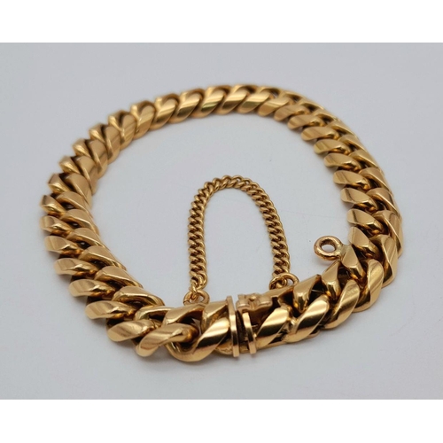 71 - A Chunky 18K Yellow Gold Curb Bracelet. Well constructed with safety chain and hanging charm attachm... 