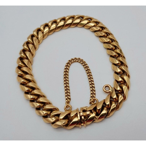 71 - A Chunky 18K Yellow Gold Curb Bracelet. Well constructed with safety chain and hanging charm attachm... 