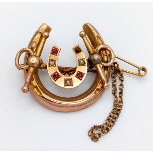 372 - An Antique 9K Gold Double Horseshoe Brooch. Seed pearl and ruby decoration. Safety chain attachment.... 