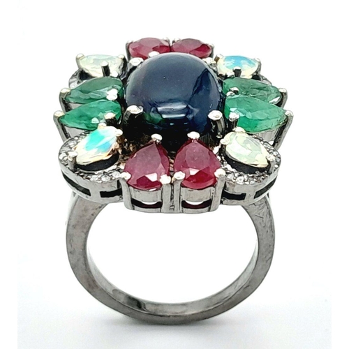 534 - A 925 silver ring featuring a central black opal, accented with emeralds, rubies, and moonstones, co... 