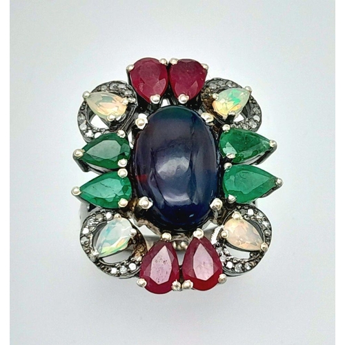 534 - A 925 silver ring featuring a central black opal, accented with emeralds, rubies, and moonstones, co... 