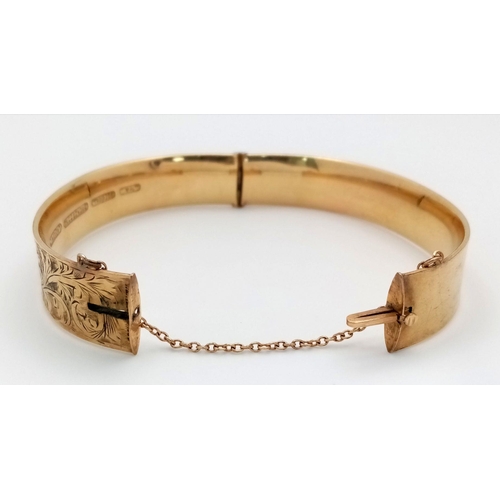 199 - A DECORATIVE HINGED BANGLE IN 9K GOLD WITH A BRONZE CORE COMES WITH SAFETY CHAIN AND IN VERY GOOD CO... 