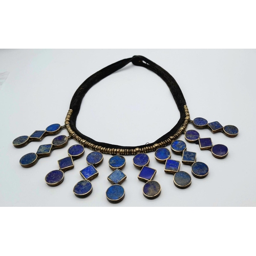 618 - A Vintage Tribal-Esque Lapis Lazuli Necklace. On white metal and textile. 47cm.