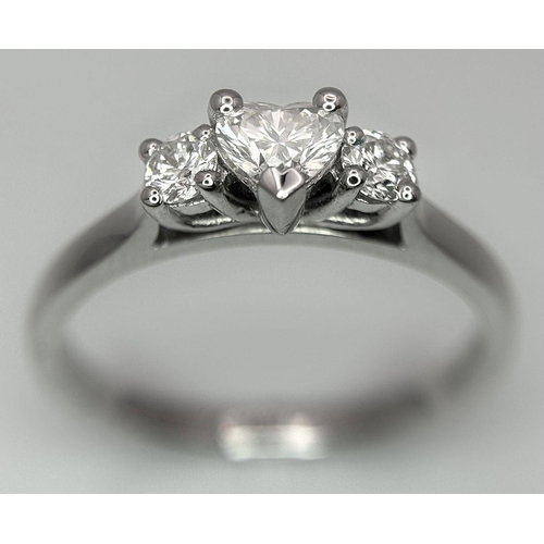 661 - An 18K White Gold and Diamond Ring. Central heart shaped diamond - 0.3ct with a 0.15ct diamond eithe... 