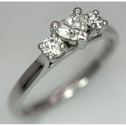 661 - An 18K White Gold and Diamond Ring. Central heart shaped diamond - 0.3ct with a 0.15ct diamond eithe... 