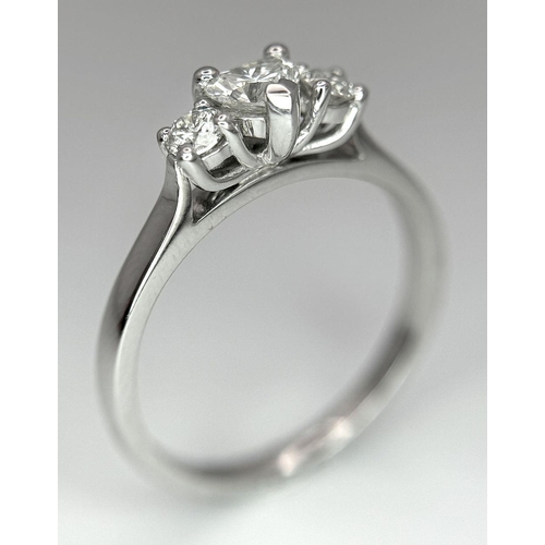 661 - An 18K White Gold and Diamond Ring. Central heart shaped diamond - 0.3ct with a 0.15ct diamond eithe... 