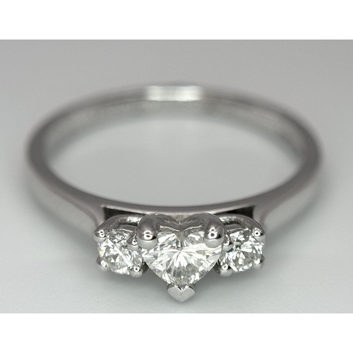 661 - An 18K White Gold and Diamond Ring. Central heart shaped diamond - 0.3ct with a 0.15ct diamond eithe... 