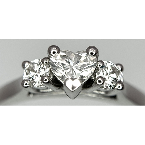 661 - An 18K White Gold and Diamond Ring. Central heart shaped diamond - 0.3ct with a 0.15ct diamond eithe... 