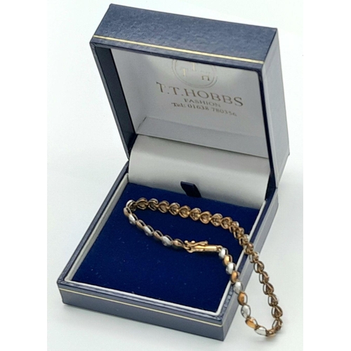 84 - An exquisite 9 carat GOLD TENNIS BRACELET. Consisting WHITE and BRONZE GOLD LINKS  in heart form, ea... 