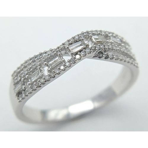 465 - A 9K WHITE GOLD DIAMOND TWIST BAND RING - WITH ROUND AND BAGUETTE CUT DIAMONDS. 0.28CTW. 2.9G. SIZE ... 