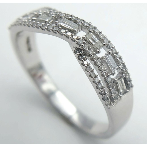 465 - A 9K WHITE GOLD DIAMOND TWIST BAND RING - WITH ROUND AND BAGUETTE CUT DIAMONDS. 0.28CTW. 2.9G. SIZE ... 