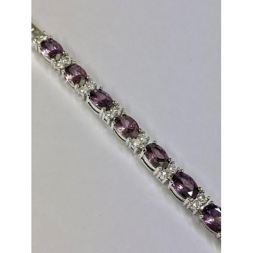 1824 - A silver tennis bracelet set with faceted amethyst stones.