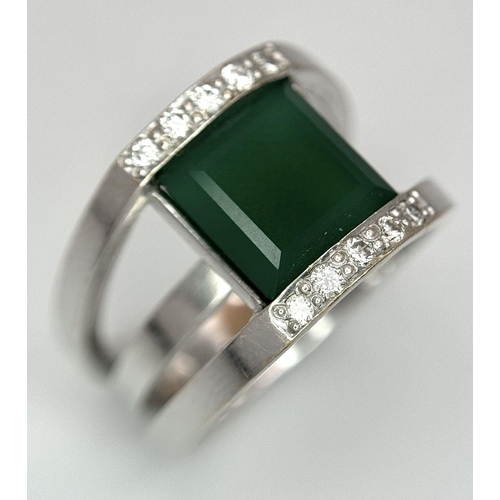 18 - A 21k White Gold, Emerald and Diamond Orbital Ring. A large 3ct square cut central emerald with diam... 