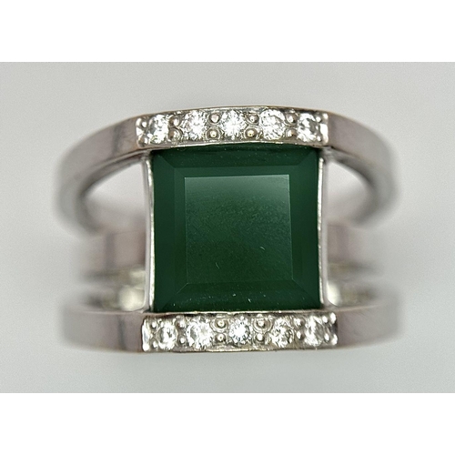 18 - A 21k White Gold, Emerald and Diamond Orbital Ring. A large 3ct square cut central emerald with diam... 