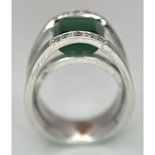 18 - A 21k White Gold, Emerald and Diamond Orbital Ring. A large 3ct square cut central emerald with diam... 