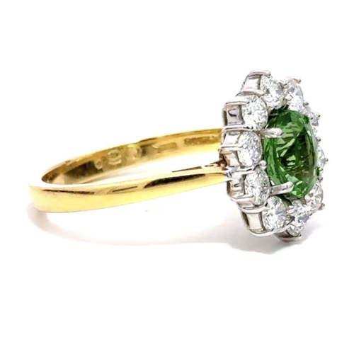 421 - An 18K Yellow & White Gold Cluster Ring, featuring a 1.30ct Oval Tsavorite surrounded by a halo of R... 