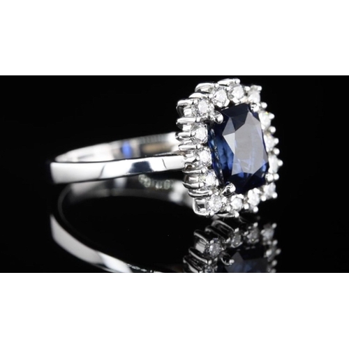 589 - A Platinum Cluster Ring, featuring a 2.05ct Emerald-Cut Blue Sapphire surrounded by a halo of Round ... 