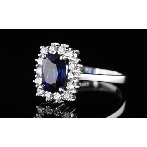 589 - A Platinum Cluster Ring, featuring a 2.05ct Emerald-Cut Blue Sapphire surrounded by a halo of Round ... 