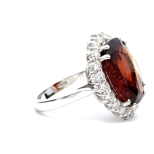 631 - An 18K White Gold Cluster Ring, featuring a 10.41ct Oval Hessonite Garnet surrounded by a halo of Ro... 