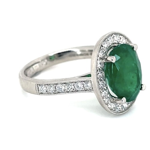 617 - An 18K Platinum Cluster Ring, featuring a 3.43ct Oval Emerald surrounded by a halo of Round Brillian... 