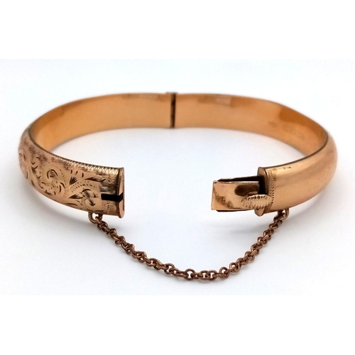 365 - A NICELY DECORATED HINGED BANGLE IN 9K GOLD METAL CORE WITH SAFETY CHAIN .    16.3gms