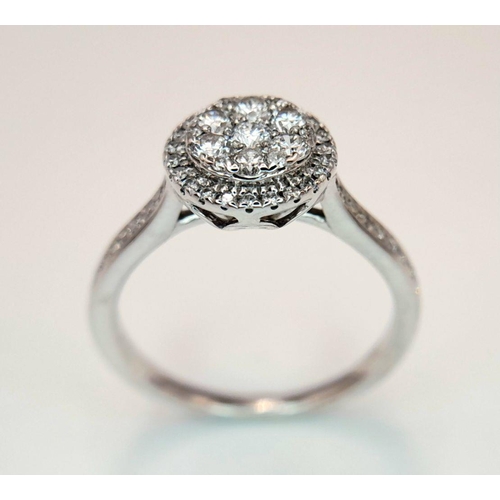 528 - A 9K White Gold Diamond Cluster Ring. Two circular levels and shoulders of diamonds. Size L 1/2. 3.4... 