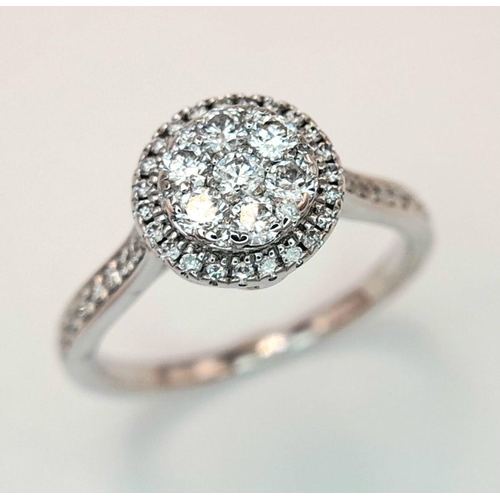 528 - A 9K White Gold Diamond Cluster Ring. Two circular levels and shoulders of diamonds. Size L 1/2. 3.4... 