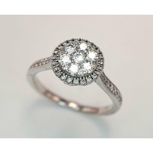 528 - A 9K White Gold Diamond Cluster Ring. Two circular levels and shoulders of diamonds. Size L 1/2. 3.4... 