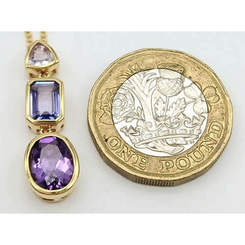 129 - A 18K YELLOW GOLD TANZANITE & AMETHYST SET PENDANT ON 45.7CM CHAIN . 27MM DROP PENDANT,  4.8G TOTAL ... 