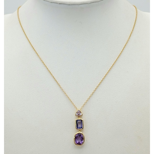 129 - A 18K YELLOW GOLD TANZANITE & AMETHYST SET PENDANT ON 45.7CM CHAIN . 27MM DROP PENDANT,  4.8G TOTAL ... 