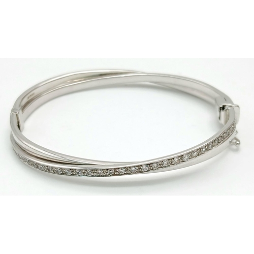 134 - A 9K White Gold White Stone Crossover Bangle. Clip design. 6cm inner diameter. 13.2g.