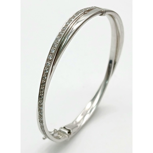 134 - A 9K White Gold White Stone Crossover Bangle. Clip design. 6cm inner diameter. 13.2g.