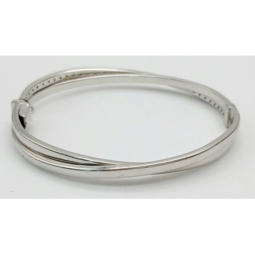 134 - A 9K White Gold White Stone Crossover Bangle. Clip design. 6cm inner diameter. 13.2g.