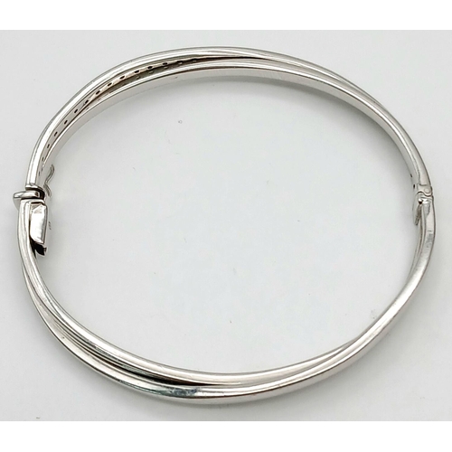 134 - A 9K White Gold White Stone Crossover Bangle. Clip design. 6cm inner diameter. 13.2g.