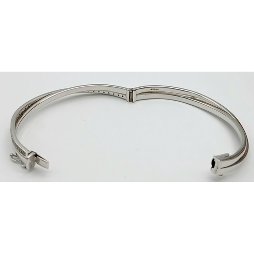 134 - A 9K White Gold White Stone Crossover Bangle. Clip design. 6cm inner diameter. 13.2g.