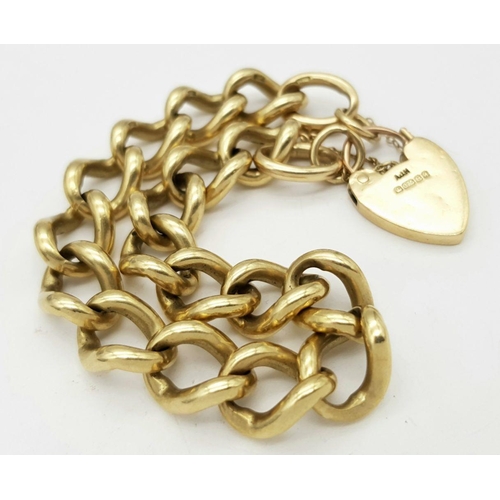 1075 - A Chunky 9K Yellow Gold Curb Link Bracelet with Heart Clasp. 18cm. 50.5g weight.